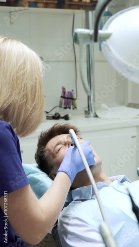 Portrait of young woman dentist sitting back examining teeth of male patient using mirror modern dentistry equipment in clinic hospital cabinet. Stomatoligy medical health care concept. Oral hygiene photo