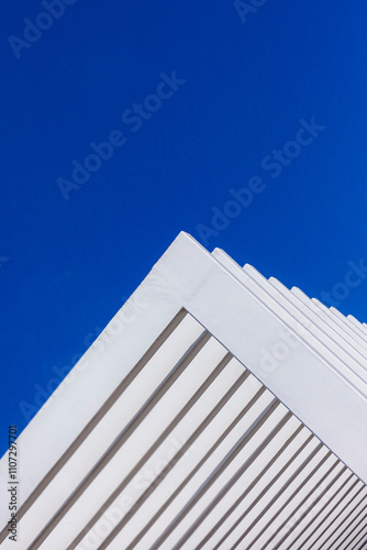 The fence on the sky background against the wall And abstract architecture contrasting with the blue sky With clear and beautiful light shadows Modern