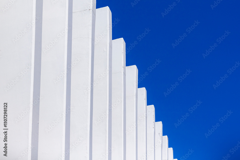 The fence on the sky background against the wall And abstract architecture contrasting with the blue sky With clear and beautiful light shadows Modern The fence on the sky background against the wall And abstract architecture contrasting with the blue sky With clear and beautiful light shadows Modern