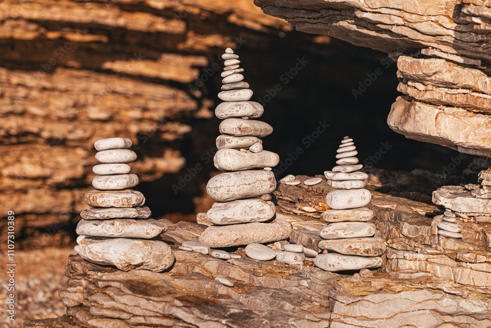 Obraz premium Balancing rock cairns overlooking tranquil ocean at sunset