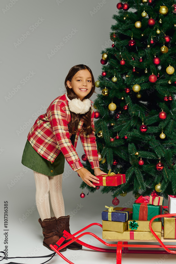 Cheerful girl places a gift under the sparkling Christmas tree with joy and excitement. Cheerful girl places a gift under the sparkling Christmas tree with joy and excitement.