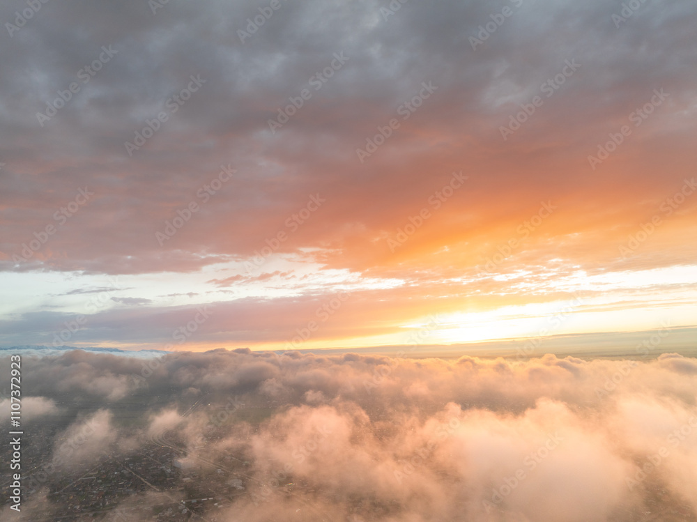 Naklejka premium Drone view of clouds at sunset. Beautiful clouds covered the city. Bright evening golden, pink and blue landscape.