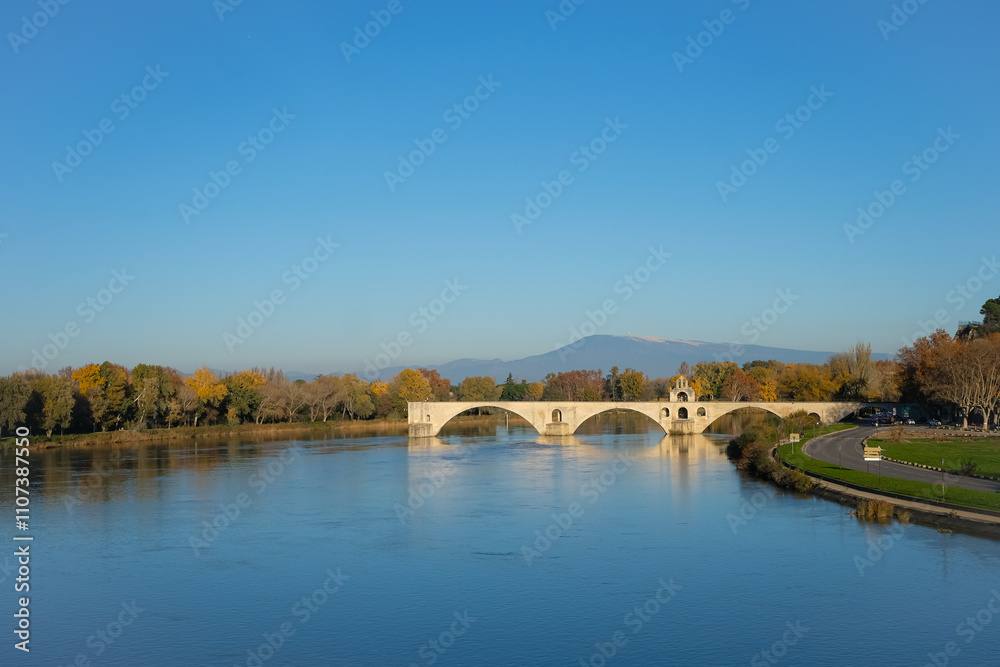 Fototapeta premium Saint-Bénézet Bridge (Pont d'Avignon) is a medieval bridge to the Rhône River, a well-known city symbol. Autumn, clear sunny day. Prealps on the horizon. Copy space. 