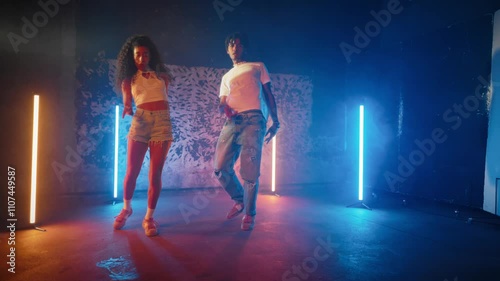 Dancers dancing in studio, attractive black woman and man, full-length shot. Pair of dancers immersed in creative flow, performing intricate modern choreography to upbeat tracks in rehearsal area