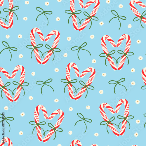 Cute red candy canes with bows, berries and holly plant berries seamless pattern on blue. Holiday season festive background. Elegant design for wrapping paper, fabric.