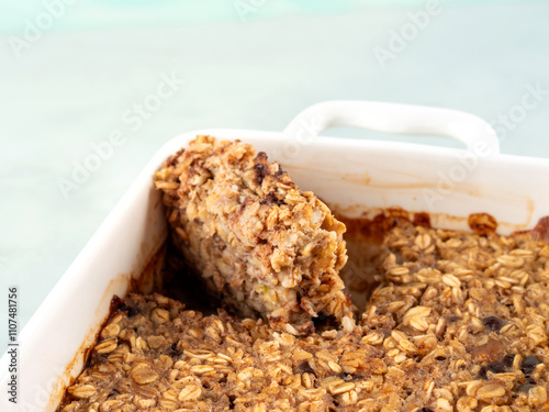 Vegan oatmeal banana cake in white baking pan on turquoise