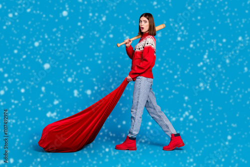 Full body profile side photo of young girl amazed hold bat santa bag still christmas isolated over blue color background