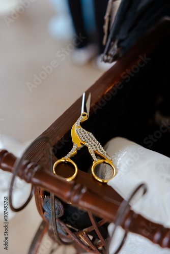 Close-up of an antique golden bird-shaped baby nail clipper resting on a vintage baby carriage