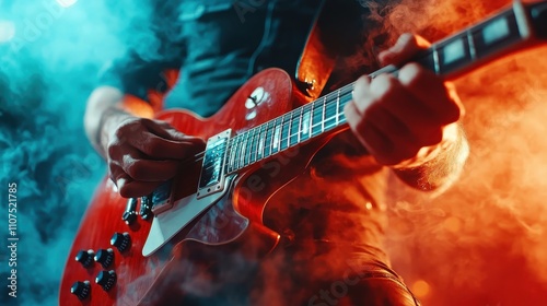 A guitarist skillfully plays an electric guitar in front of a striking stage backdrop featuring vibrantly contrasting blue and red lights filled with smoke and energy. photo