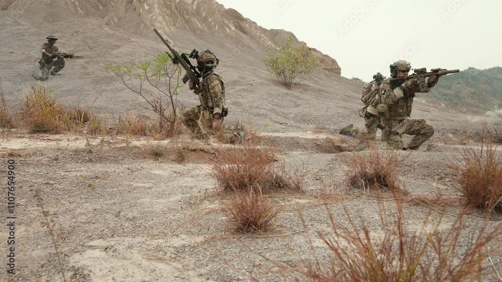 Soldiers in camouflage uniforms aiming with their rifles ready to fire during military operation in the desert