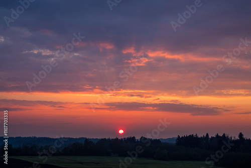 Feuerroter Sonnenuntergang in Bayern mit rosa Wolken photo