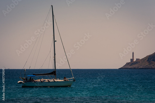 Sailboat at anchor in front of the Punta Palascia Lighthouse. photo