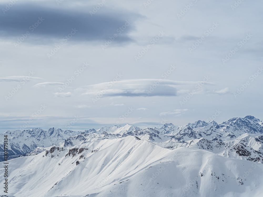 Obraz premium Snow-covered alpine peaks under cloudy sky