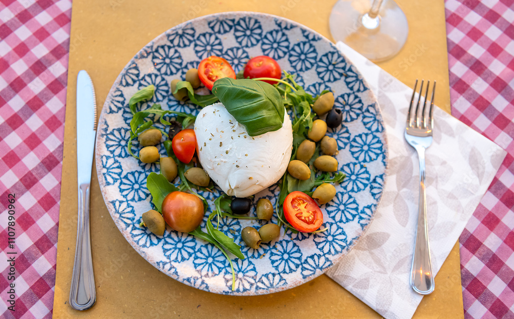 Plate with Italian Bufala mozzarella, tomatoes and olives. Top view. Serving in a restaurant.