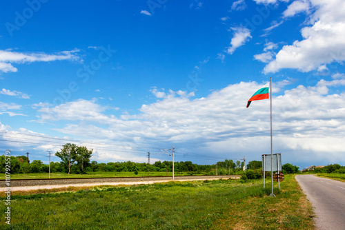 Railway tracks and the Bulgarian national flag under cloudy May sky at the exit of the village of Krum in direction of the town of Dimitrovgrad in Haskovo Province, Southern Bulgaria photo