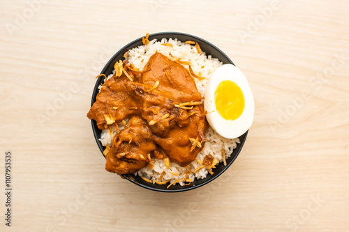 Butter Chicken Rice Pulao with boiled egg served in bowl isolated on table side view of indian and bangladeshi food photo