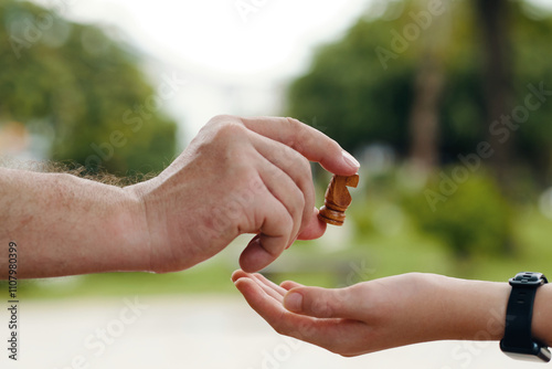 Grandfather giving a knight chess piece to his grandson during their game outdoors