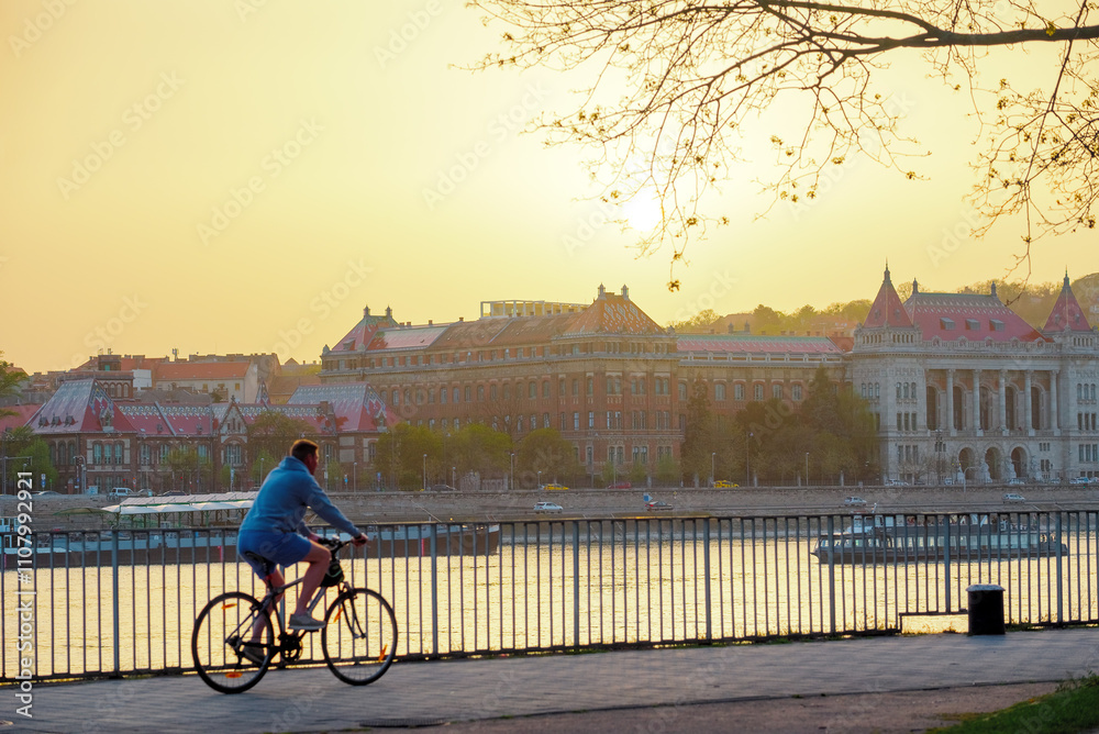 Fototapeta premium Person riding a bike in the park against old city view