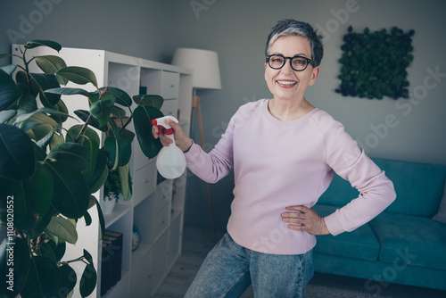 Photo of positive good mood woman dressed pink sweatshirt enjoying plants clean up indoors house apartment room photo