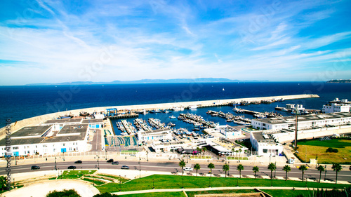 The port of Tangier with its numerous boats, bordered by the shimmering blue sea and the Strait of Gibraltar.