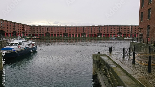 Liverpool, UK - 2.3.2018: Converted red brick warehouses in Royal Albert Dock with yacht and sailing boats berthed on the side under a cloudy sky before the pandemic, view from Salthouse Quay photo