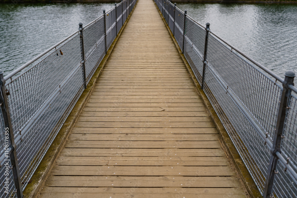 Obraz premium A small pedestrian bridge over a calm water surface
