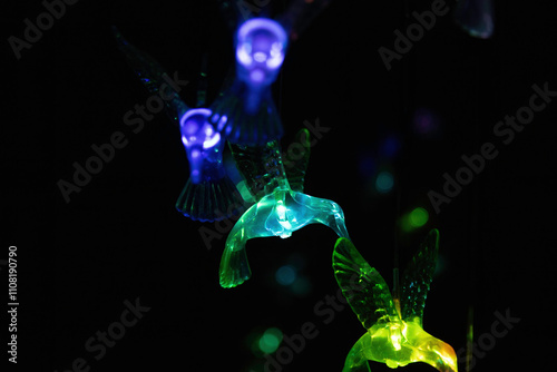 Illuminated glass animal ornaments hanging in darkness, nobody
