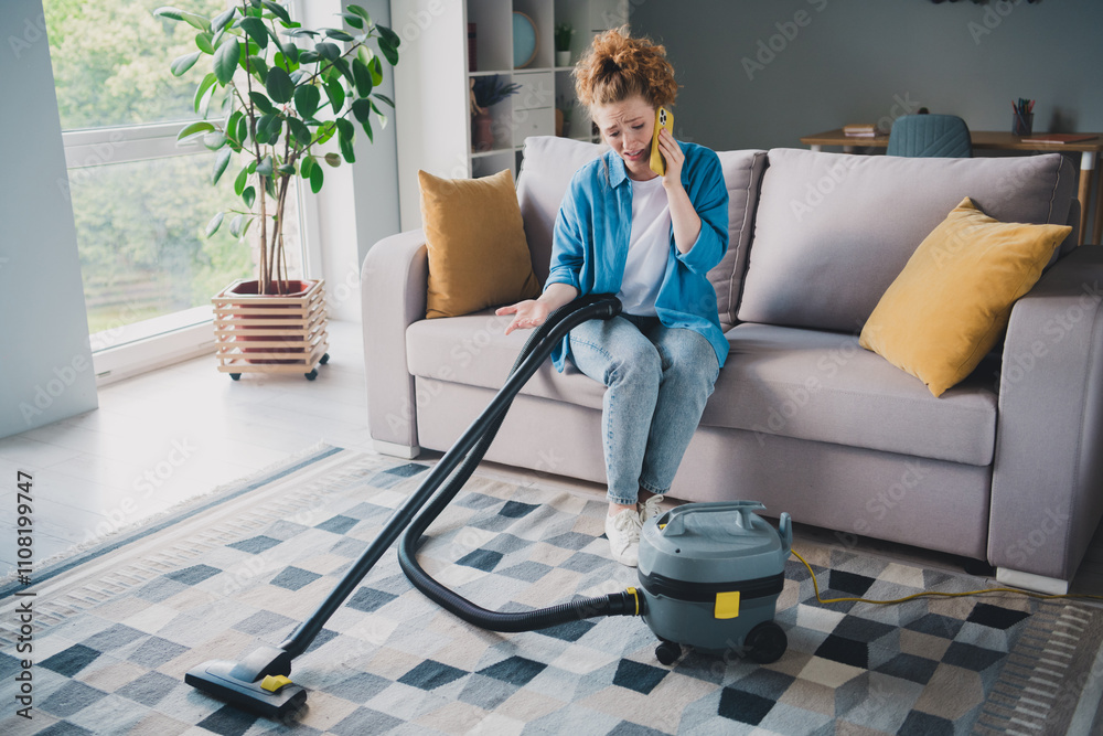 Fototapeta premium Full body photo of ginger young girl stressed repair vacuum cleaner talk phone wear blue clothes enjoy modern cozy interior flat indoors