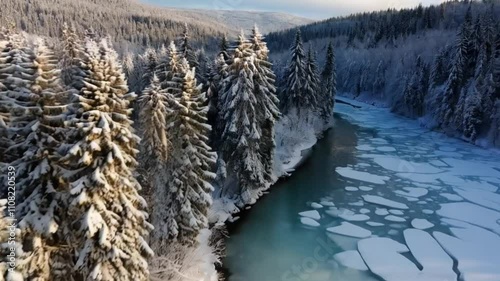 A breathtaking drone view of a frozen river winding through a dense forest blanketed in snow.