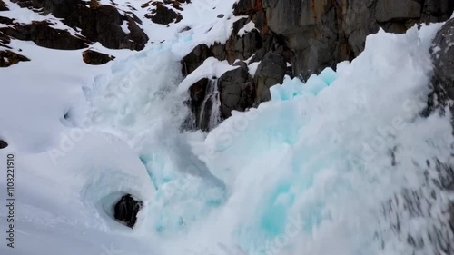 A dramatic close-up of a snow avalanche tumbling down a mountain cliff. 