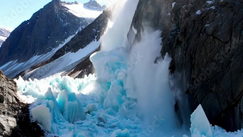 An intense shot of a colossal avalanche descending from a glacier-capped peak.