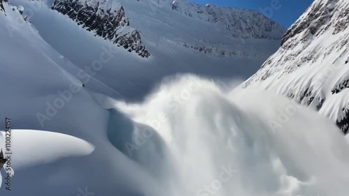 A wide-angle view of an avalanche sweeping through a snowy mountain valley.