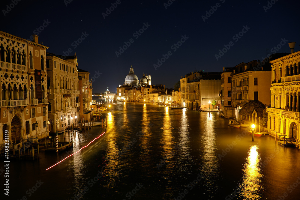 Fototapeta premium Venice, Italy: Night view of Venice Grand Canal with boats and Santa Maria della Salute church on sunset from Ponte dell'Accademia bridge. Venice, Italy