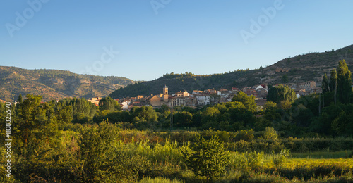 Panoramic view of a village in the middle of the countryside illuminated by the last rays of the sunset. Casas Altas in Rincón de Ademuz, Spain, summer 2023