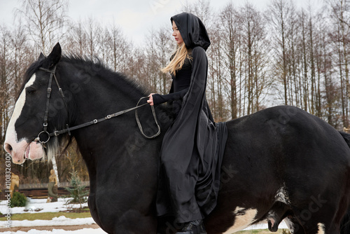 Картината върху платно woman princess in black cloak sits astride black steed horse