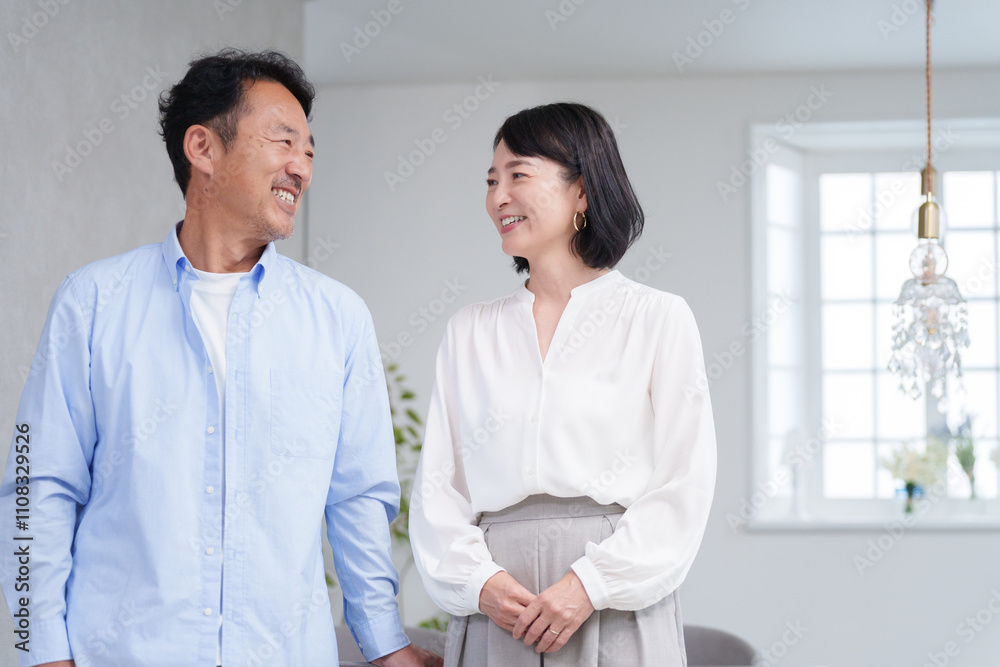 家のリビングで過ごす笑顔のミドル夫婦 家のリビングで過ごす笑顔のミドル夫婦