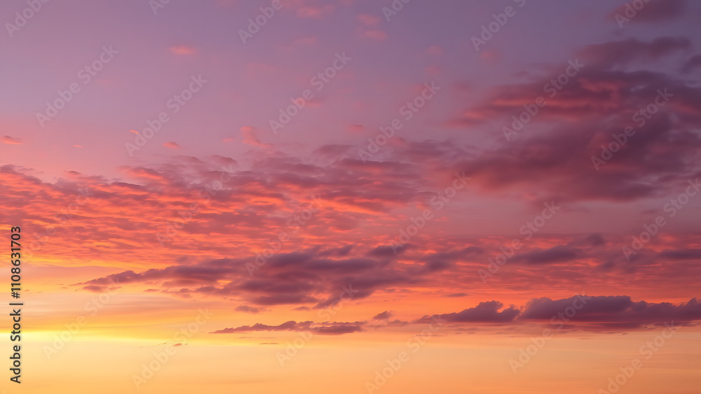 Fototapeta premium A serene dusk sky featuring layers of orange and deep purple with scattered cloud textures