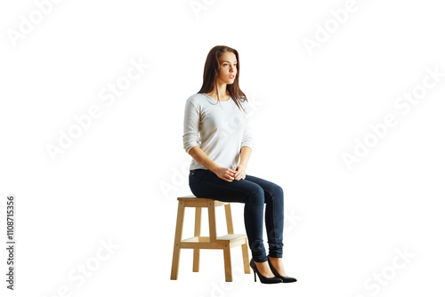 Konstfotografi A young woman sitting on a wooden stool wearing a casual outfit, isolated on a white background