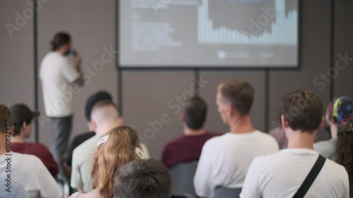Wallpaper Mural Group of people attentively listening to a speaker presenting data on a screen in a conference setting. The room is filled with individuals focused on the presentation. Torontodigital.ca