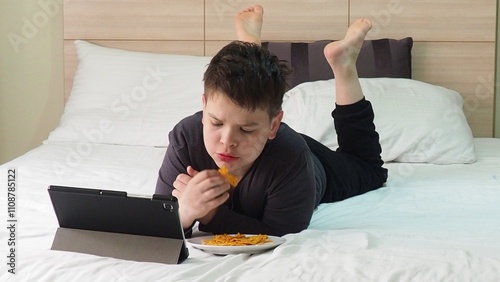 Smiling teenage school kid using tablet computer, relaxing on sofa at home, watching learning video, movie, online class, listening to music, communicates with friends, social networks