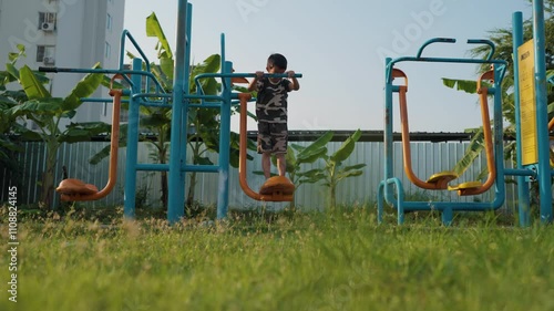 Little asian boy enjoy play swing in outdoor playground grass kid relax