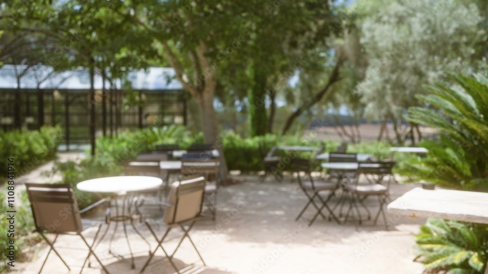 Blurred outdoor cafe setting in mallorca with defocused tables, chairs, and lush greenery in the background under bright sunlight. Blurred outdoor cafe setting in mallorca with defocused tables, chairs, and lush greenery in the background under bright sunlight.