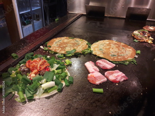 Okonomiyaki is a savory Japanese pancake made with batter, cabbage, and various toppings like meat, seafood, and sauces, a tasty and famous dish, popular especially in Osaka and Hiroshima.