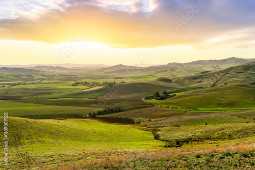 beautiful green valley with green fields with green spring grass with nive hills and mountains and scrnic colorful cloudy sunset on background of landscape photo