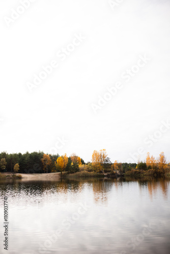 Beautiful landscape of a lake in the middle of an autumn forest. Reflection of trees in the lake water