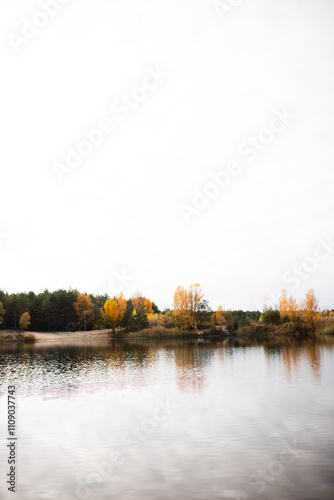 Beautiful landscape of a lake in the middle of an autumn forest. Reflection of trees in the lake water