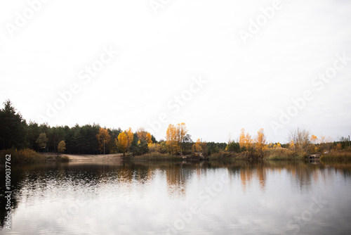 Beautiful landscape of a lake in the middle of an autumn forest. Reflection of trees in the lake water