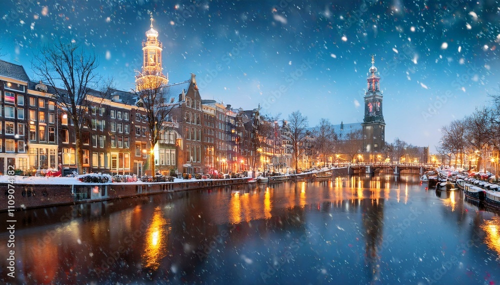 Fototapeta premium enchanting winter cityscape of amsterdam with snow falling over illuminated historic buildings and church spires reflected in calm canal waters at dusk