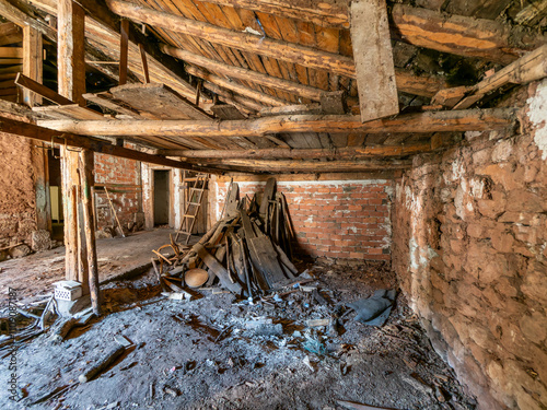 Abandoned farmhouse interior showing decaying wooden roof and debris photo