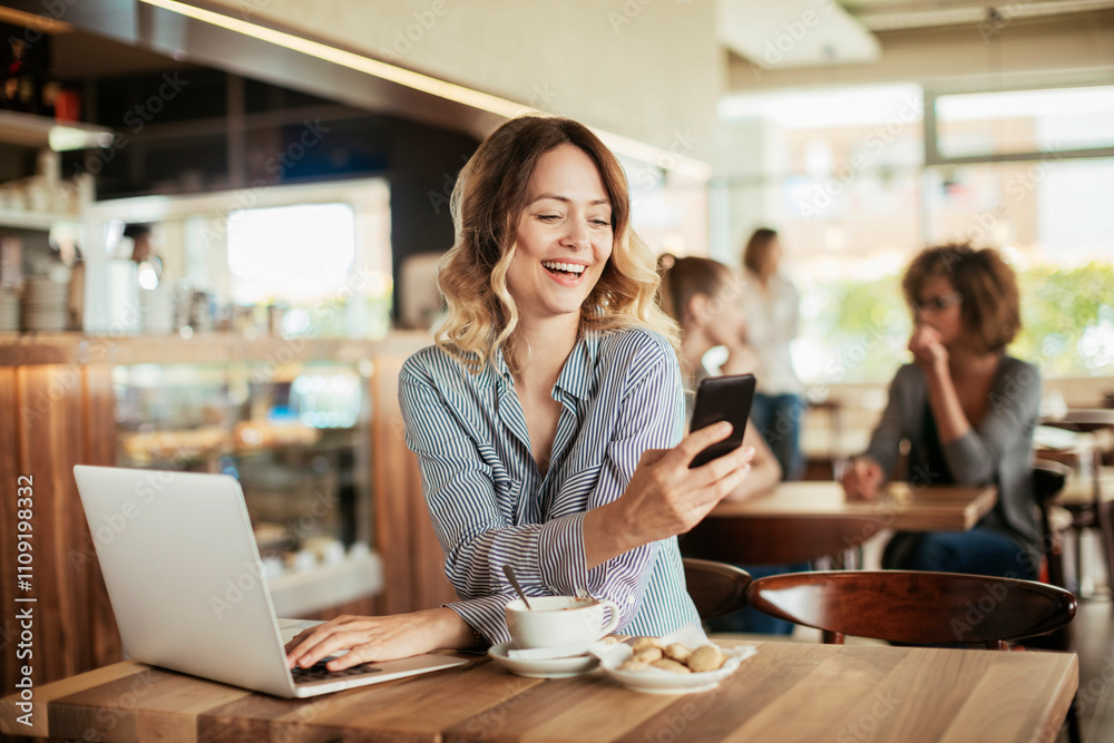 Fototapeta premium Young woman using a phone while having coffee in a cafe